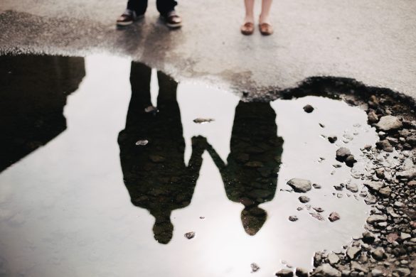 Couple holding hands mirrored on the calm surface of a river