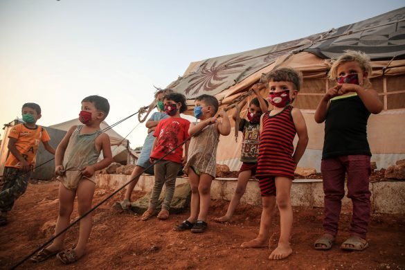 A group of children next to a tent at a refugee camp